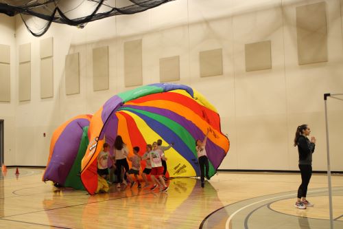 Children playing with rainbow parachute